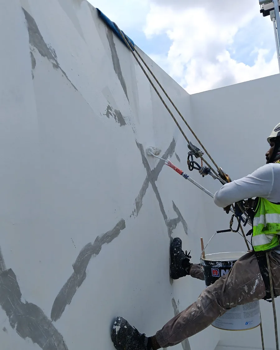 Painter sealing repaired cracks on an exterior wall before repainting