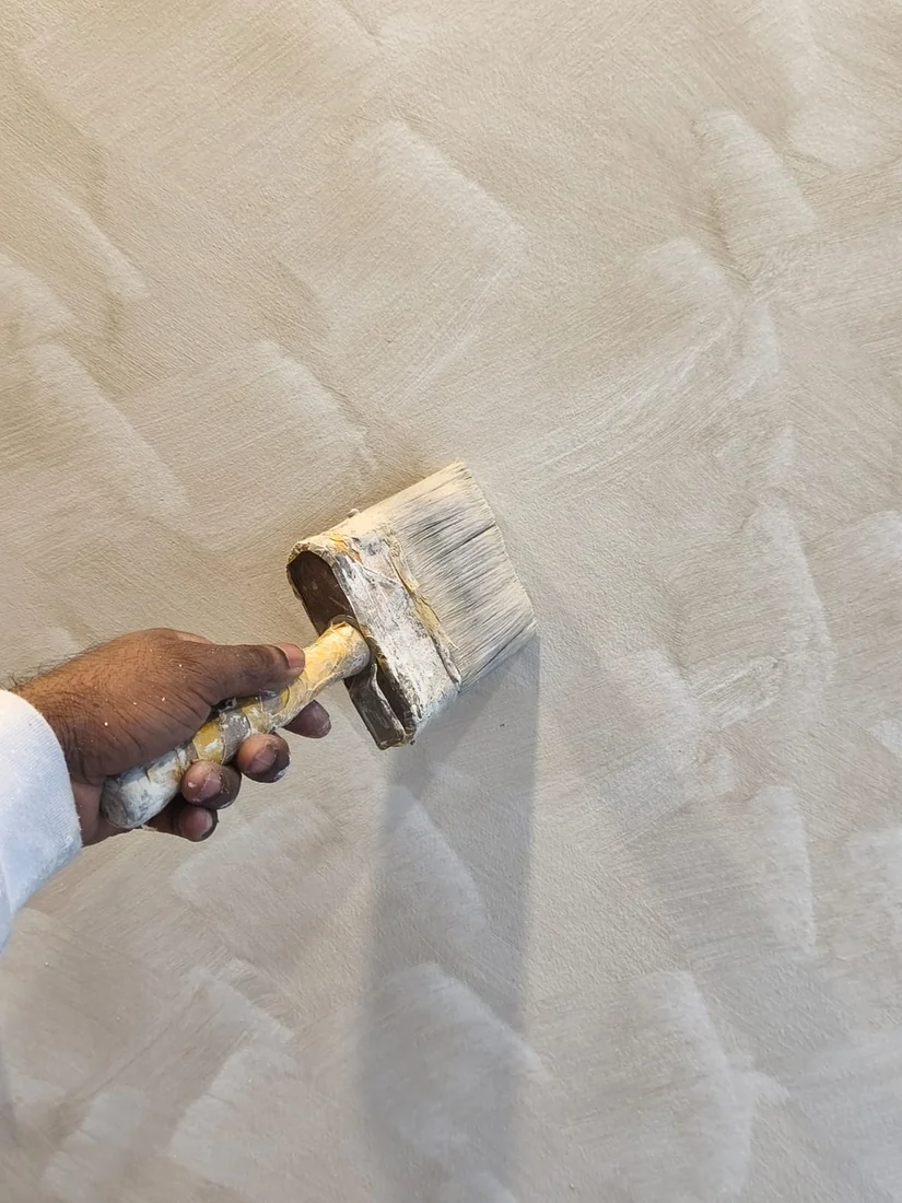 Painter hand-brushing limewash to build its soft, mineral texture