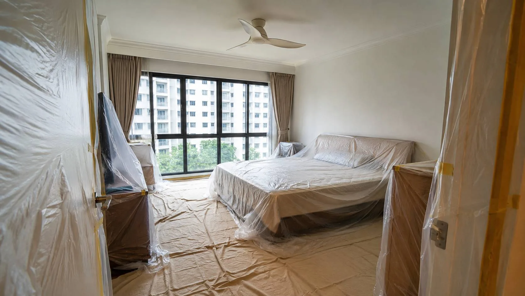Bedroom furniture and floors sealed under protective sheeting before treatment
