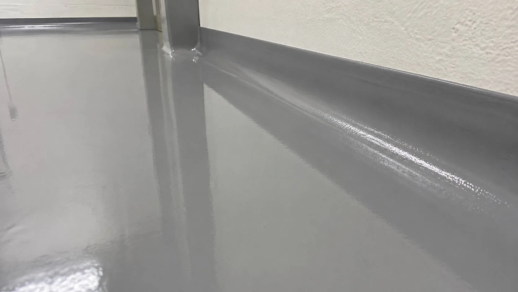 Glossy grey epoxy floor with coving detail and reflection